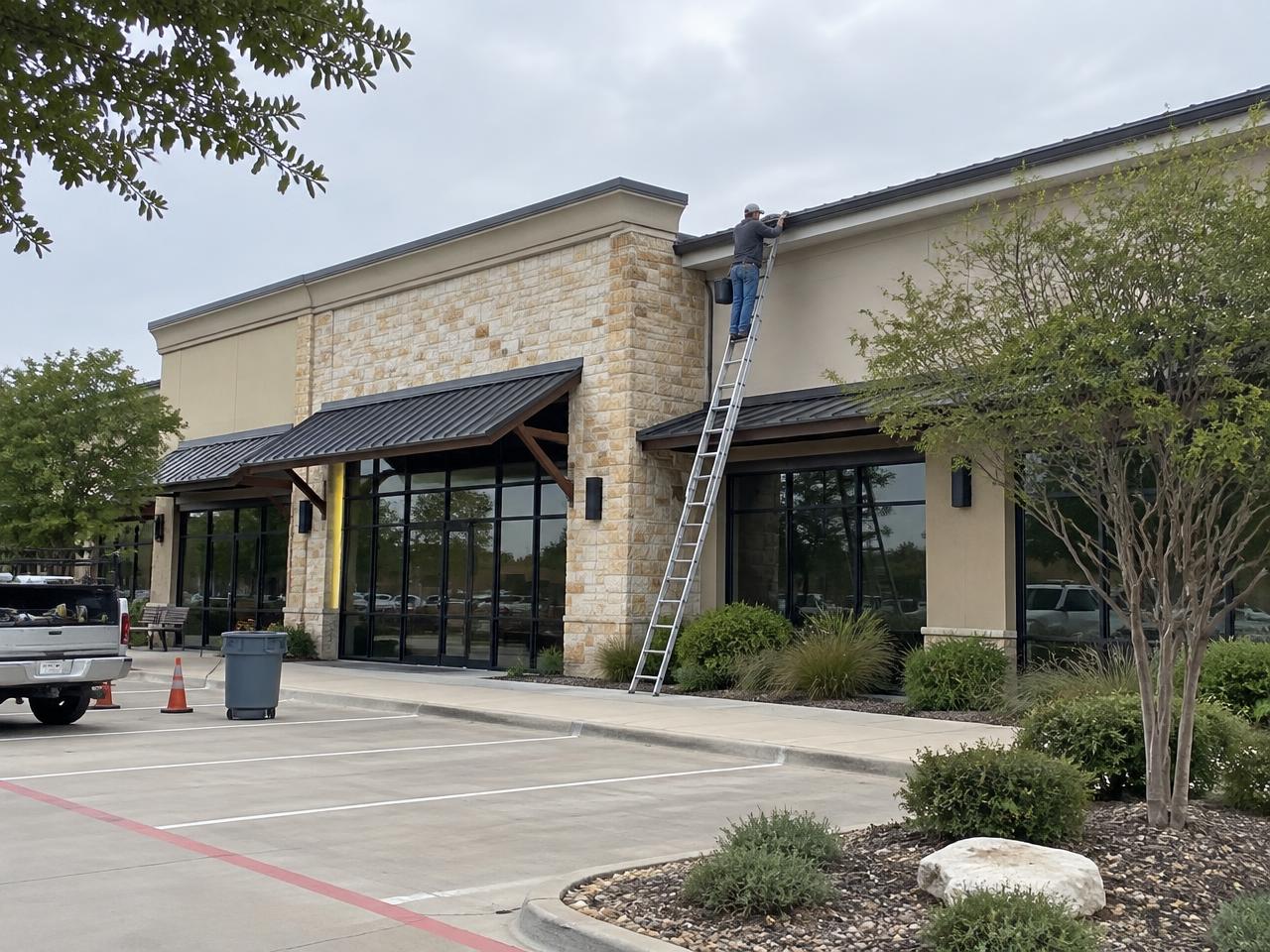 Worker pressure washing the exterior of a commercial retail building
